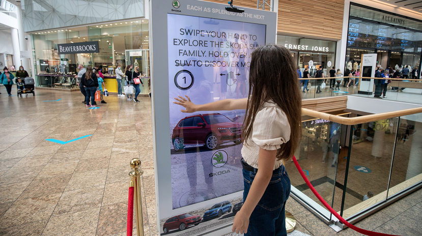 young girl using hand gestures in front of digital ooh advertising example